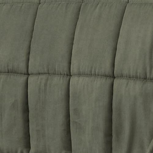Close-up of green quilted fabric with vertical stitching.
