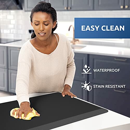 Person cleaning a kitchen counter mat that is waterproof and stain resistant.