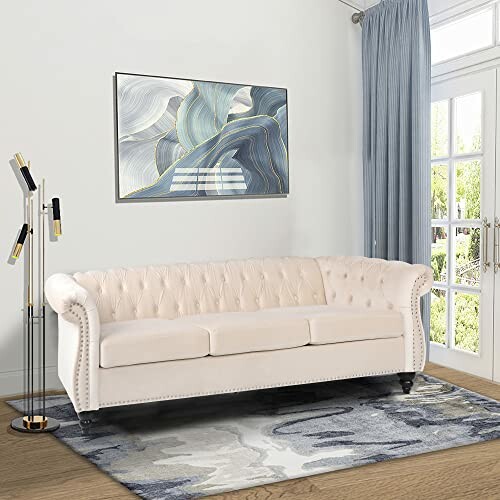 Elegant living room with a cream tufted sofa, abstract wall art, and a tall floor lamp by a window.